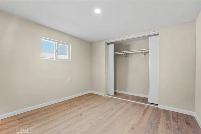 a view of an empty room with wooden floor and closet