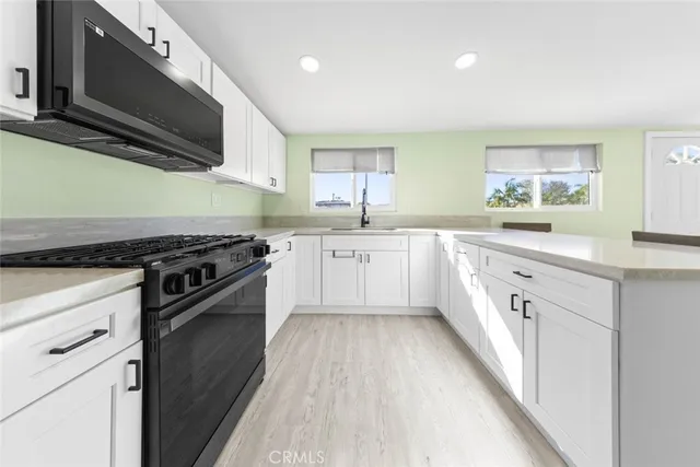 a kitchen with stainless steel appliances granite countertop a stove a sink and a microwave