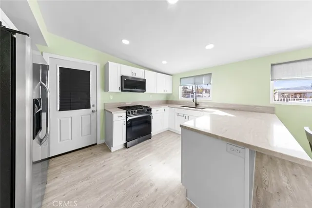 a kitchen with stainless steel appliances granite countertop a stove top oven a sink and a refrigerator with wooden floor