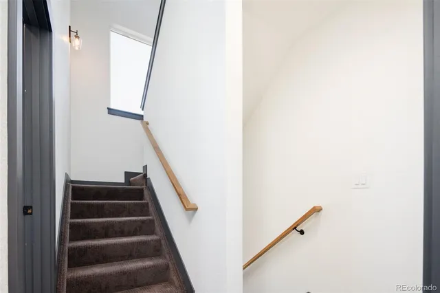 a view of staircase with wooden floor and white walls