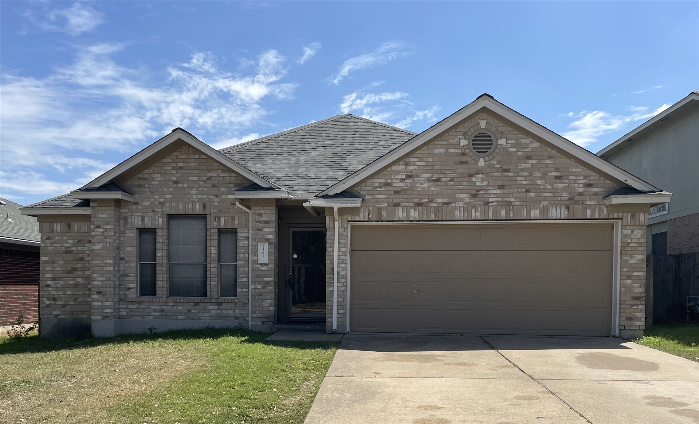 View of front of house featuring a garage, brick siding, driveway, a front lawn, and roof with shingles