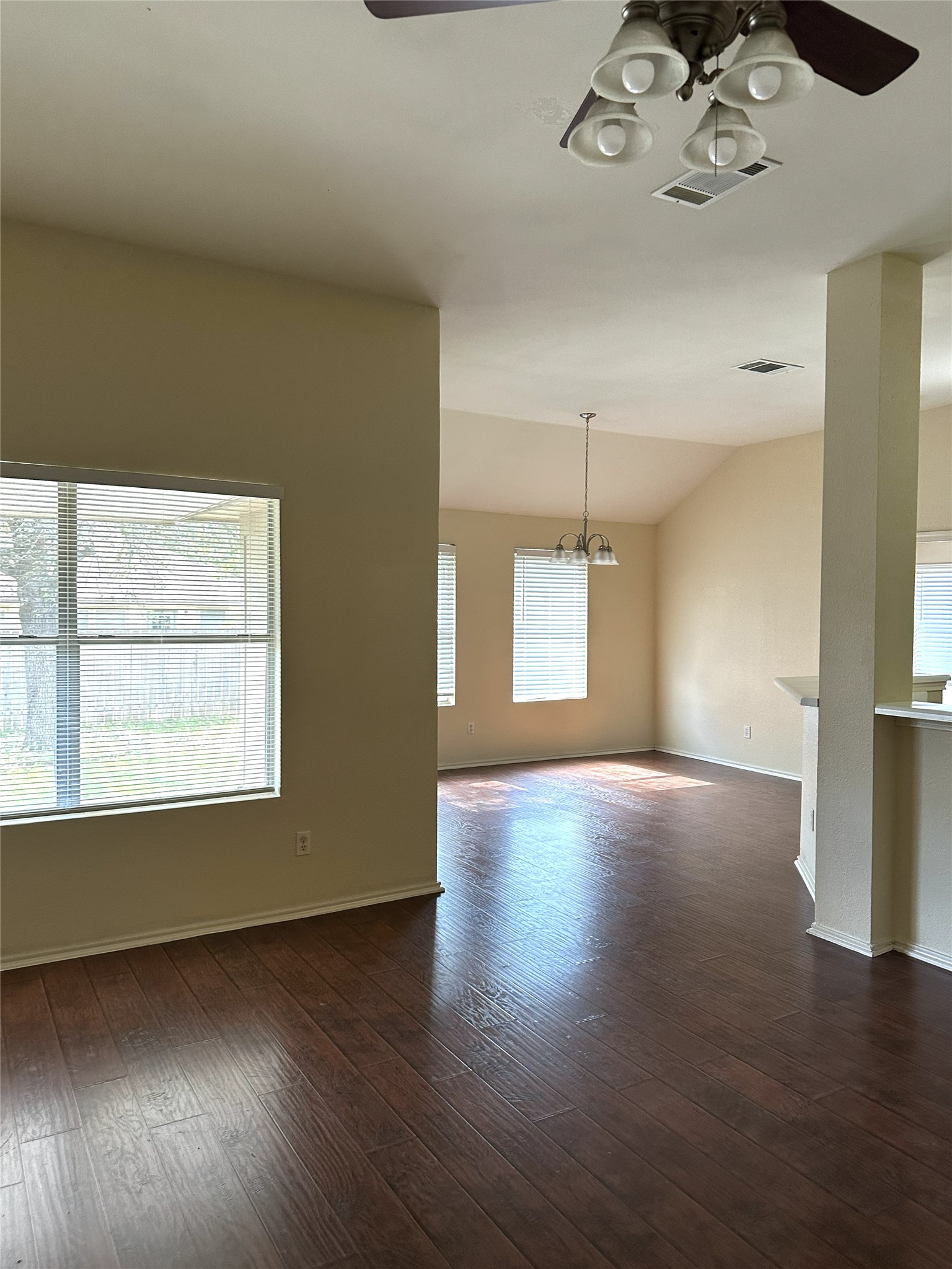 13915 Randalstone Drive Pflugerville, TX 78660 - Photo 5 of 19 Empty room featuring ceiling fan, lofted ceiling, a chandelier, and dark wood-style floors