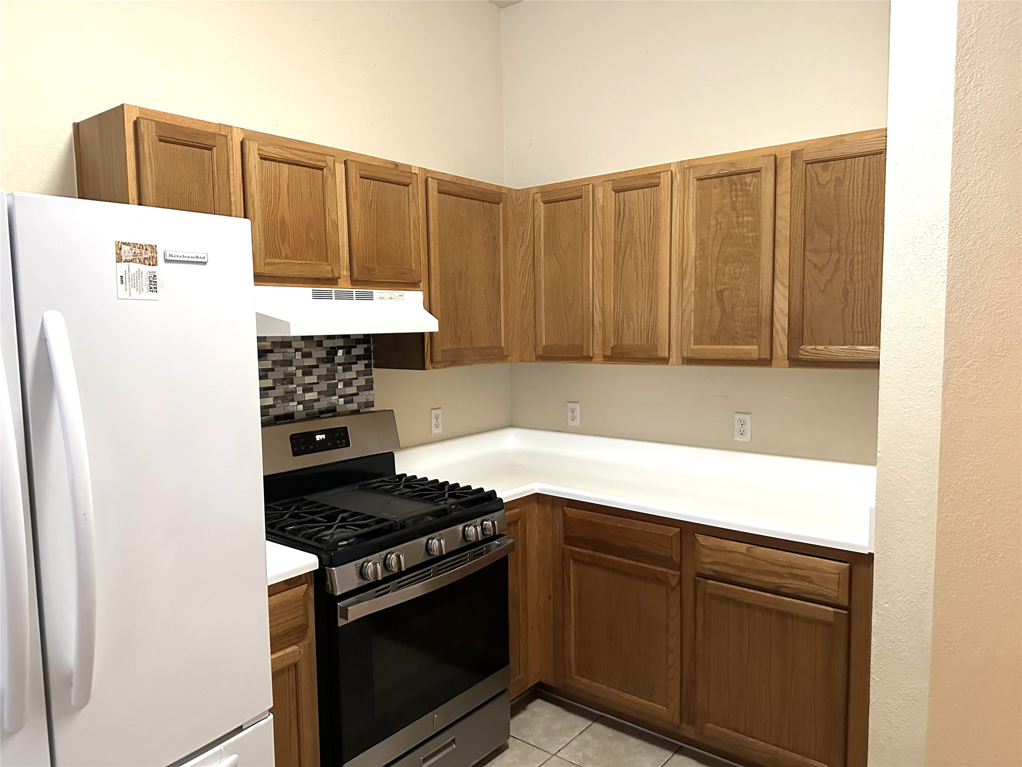 13915 Randalstone Drive Pflugerville, TX 78660 - Photo 8 of 19 Kitchen with freestanding refrigerator, stainless steel range with gas cooktop, light countertops, tasteful backsplash, and wood finish cabinetry