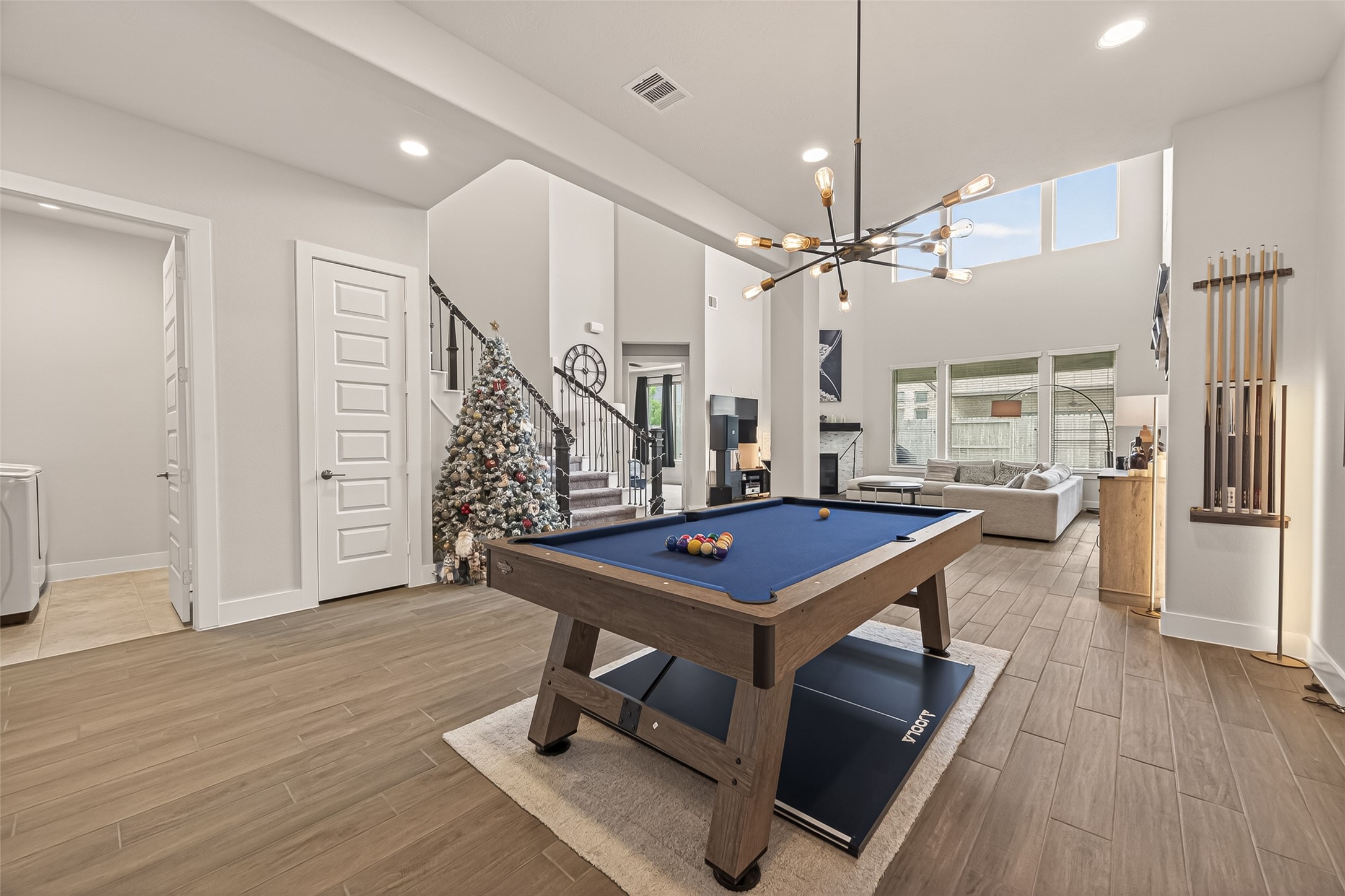1815 Brea Rdg Trail Katy, TX 77494 - Photo 5 of 43 This spacious, open-concept living area features high ceilings, a modern chandelier, and large windows for natural light. It includes a stylish pool table and connects to a cozy seating area, perfect for entertaining.