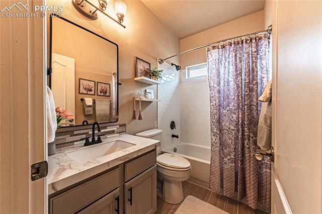 13812 Windy Oaks Road Colorado Springs, CO 80921 - Photo 6 of 50 Bathroom featuring a textured wall, toilet, vanity, and shower / bath combo with shower curtain