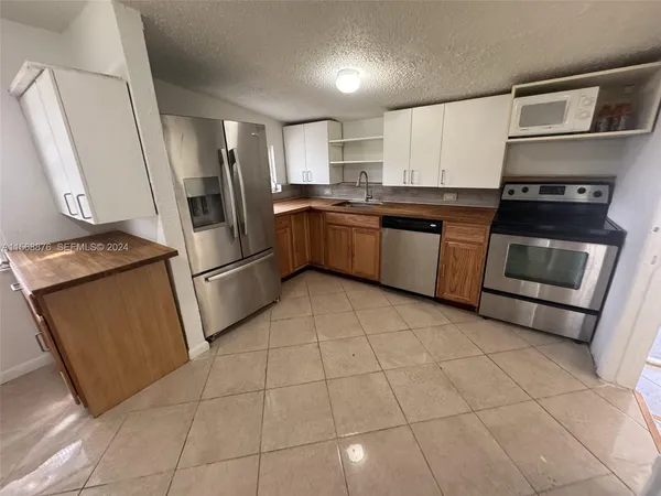 a kitchen with granite countertop a refrigerator and a stove top oven