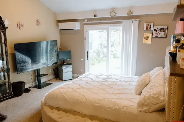 a bedroom with a bed and a flat tv screen on the dresser