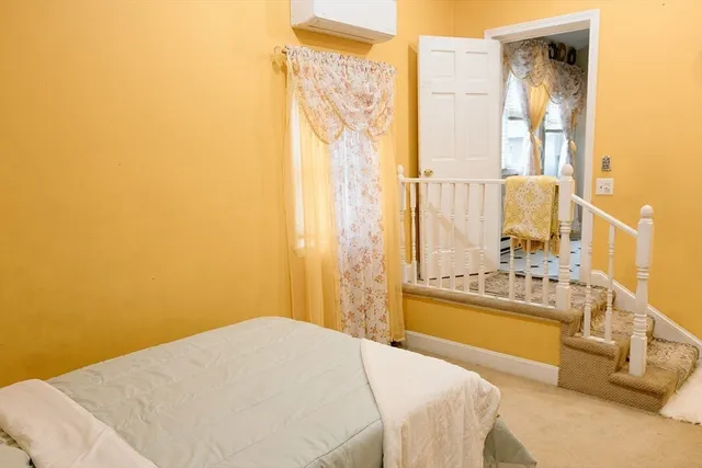 a bedroom with a bed and a large mirror next to a window