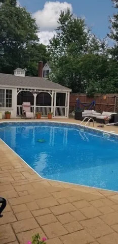a view of backyard with swimming pool and seating space