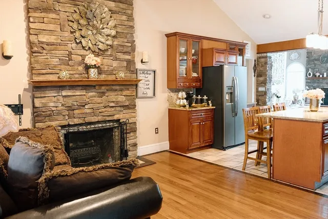 a living room with stainless steel appliances furniture a fireplace a flat screen tv and a large window