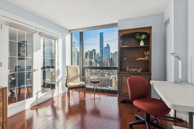 a living room with furniture a lamp wooden floor and a large window