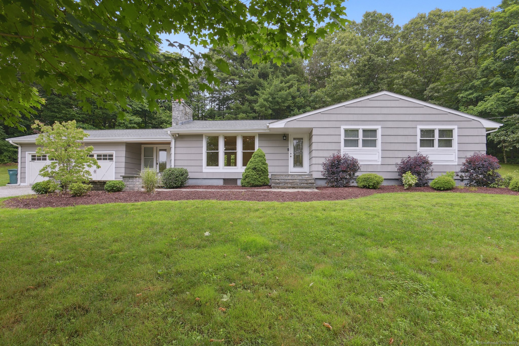a front view of a house with a yard and trees