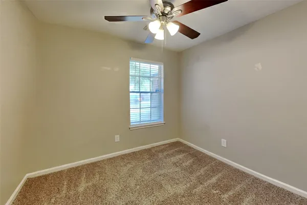 an empty room with a window and a fan