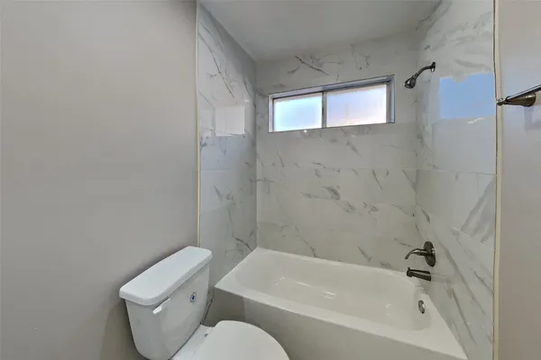 a white toilet sitting next to a bathtub