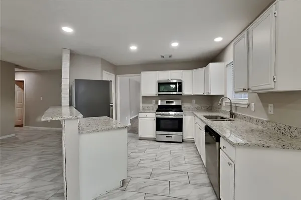 a kitchen with granite countertop a refrigerator and a stove top oven