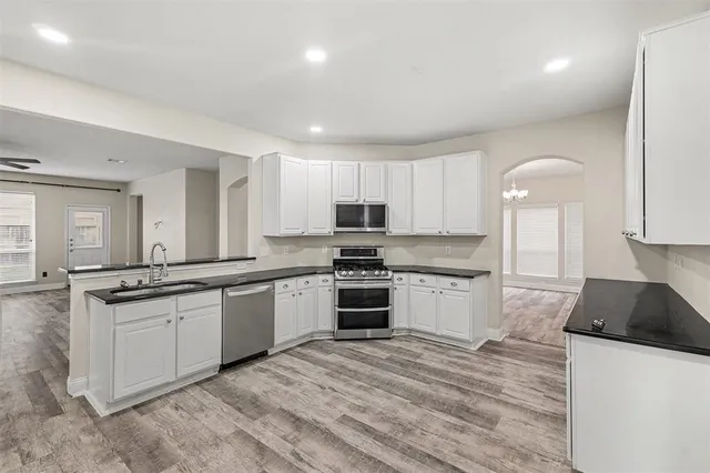 a kitchen with granite countertop a stove top oven sink and cabinets