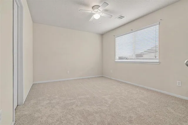 an empty room with a window and a fan