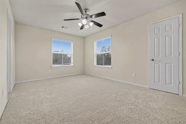 an empty room with windows and fan