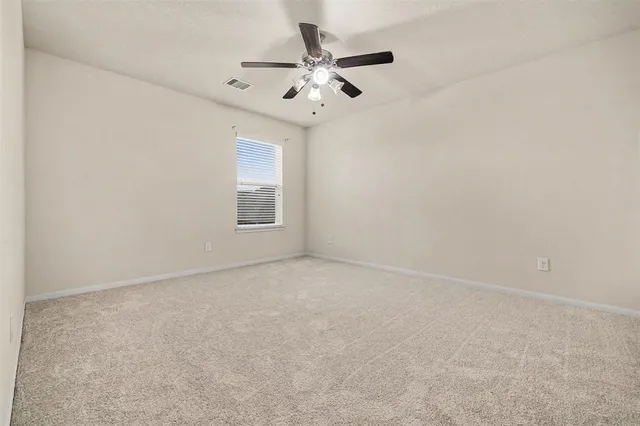 an empty room with a chandelier fan and windows