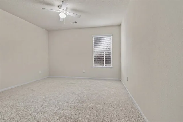 an empty room with windows and fan