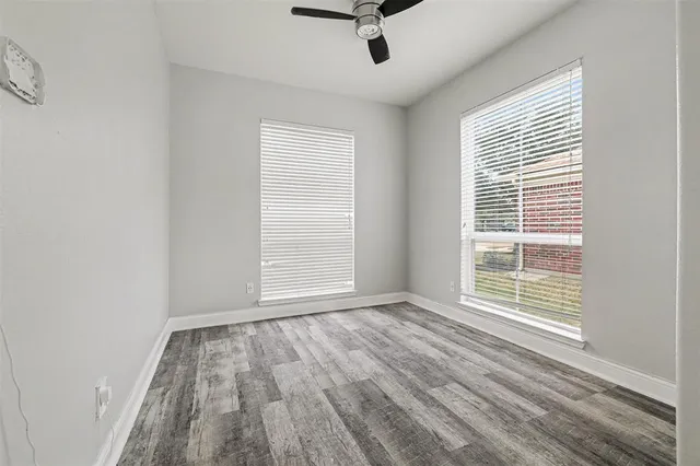 a view of an empty room with a window and wooden floor