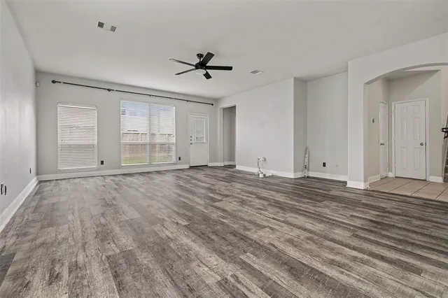 a view of empty room with wooden floor and fan