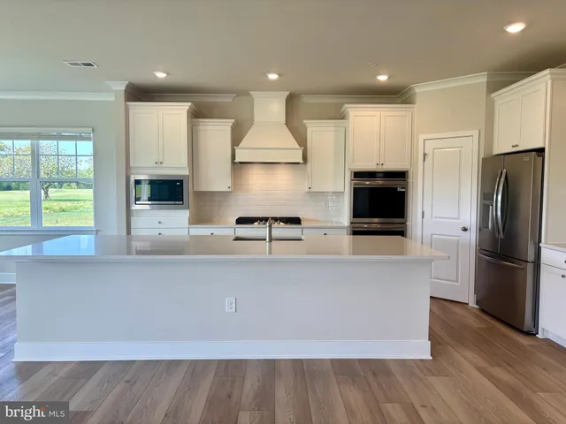 a large kitchen with stainless steel appliances a large counter top a stove and a refrigerator