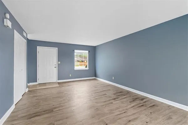 a view of an empty room with wooden floor and a window