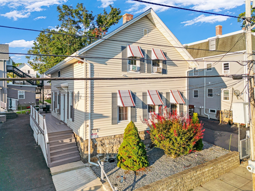 a view of a house with wooden stairs and a bench
