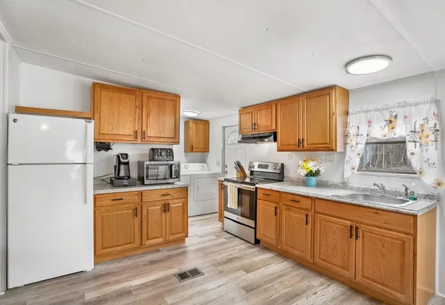 a kitchen with granite countertop wooden floors stainless steel appliances a sink and a window