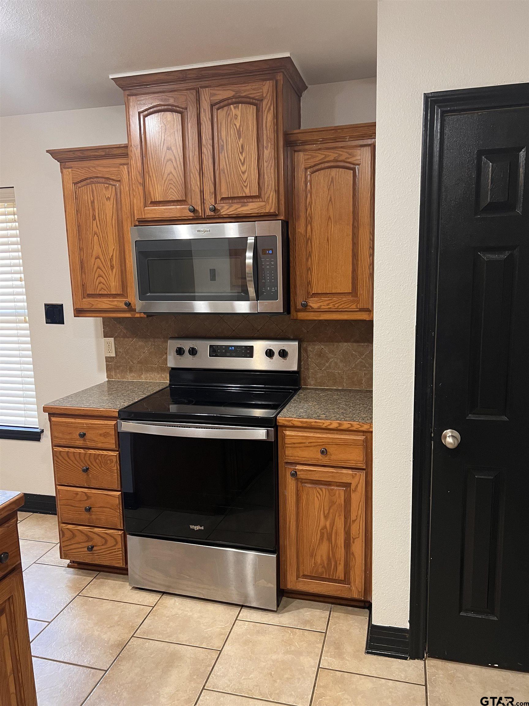 19482 Ruggles Court Flint, TX 75762 - Photo 11 of 16 a kitchen with granite countertop a stove and a microwave