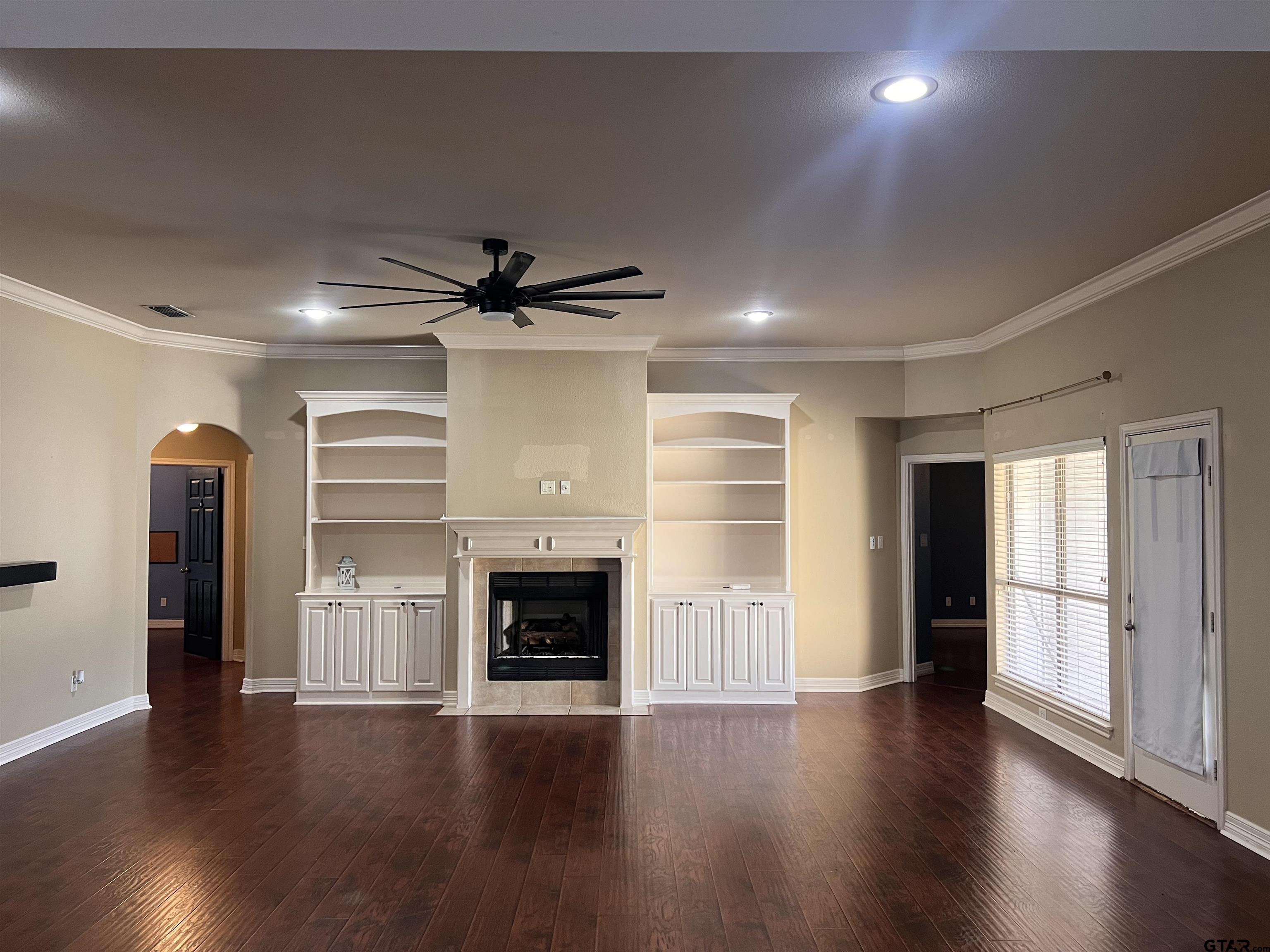 19482 Ruggles Court Flint, TX 75762 - Photo 6 of 16 an empty room with wooden floor a fireplace and windows