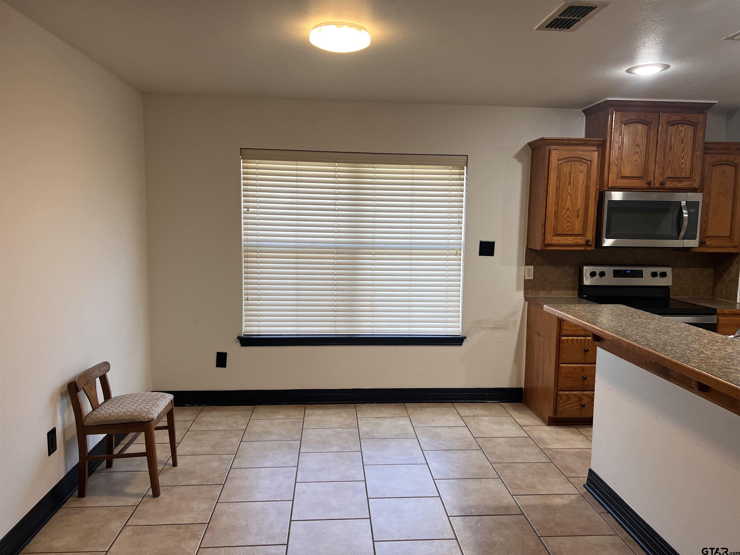 19482 Ruggles Court Flint, TX 75762 - Photo 10 of 16 a kitchen with stainless steel appliances granite countertop a stove a sink and a microwave