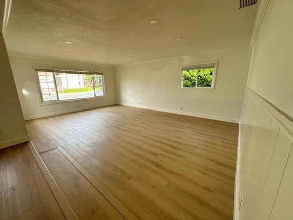an empty room with wooden floor and windows