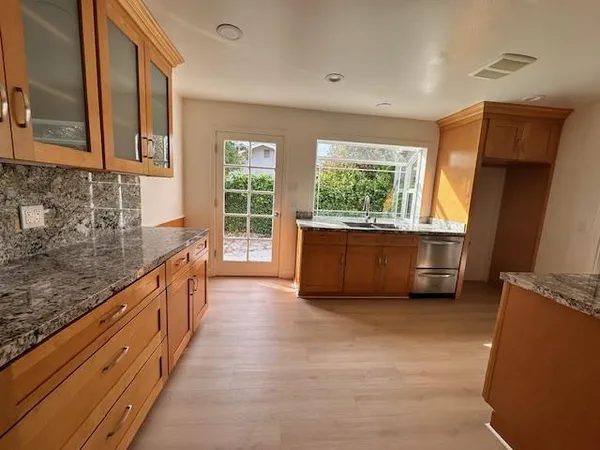 a large kitchen with granite countertop a sink and dishwasher a stove top oven with wooden floor