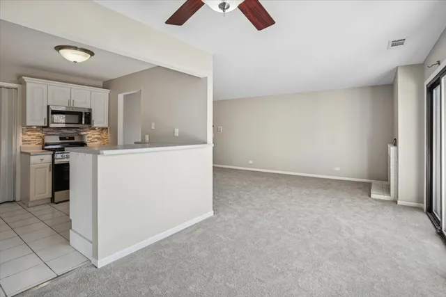 a living room with stainless steel appliances kitchen island granite countertop a refrigerator oven a stove top oven a sink and dishwasher