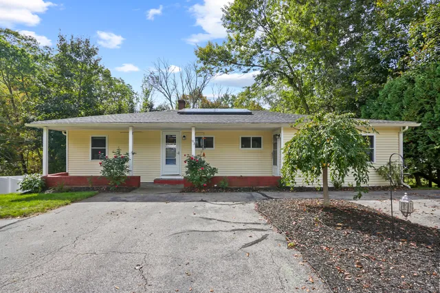 front view of house with potted plants and a yard