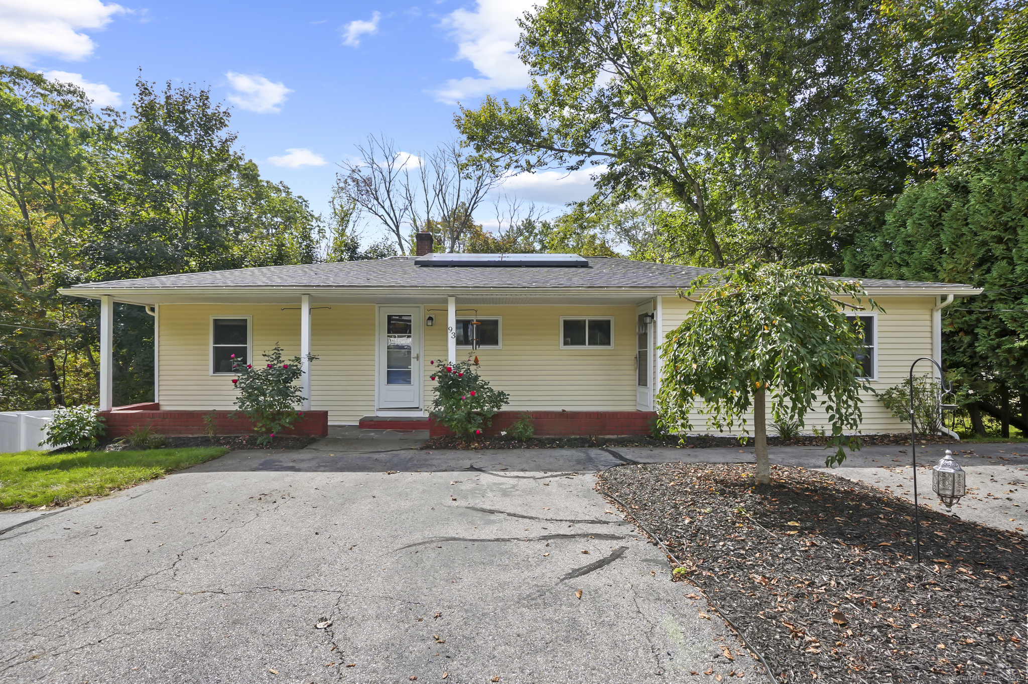 front view of house with potted plants and a yard
