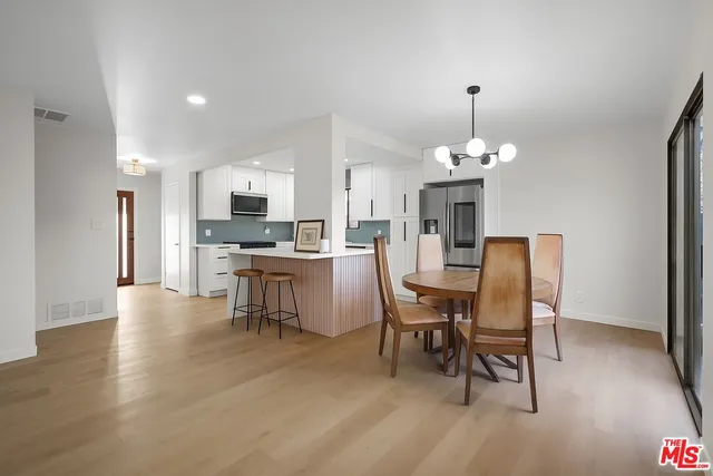 a dining room with kitchen island stainless steel appliances kitchen island granite countertop a table chairs a sink and a refrigerator