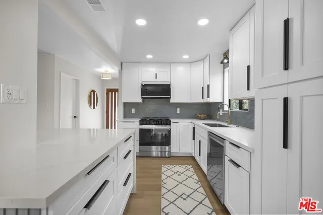 a large kitchen with stainless steel appliances granite countertop a stove a sink and a refrigerator