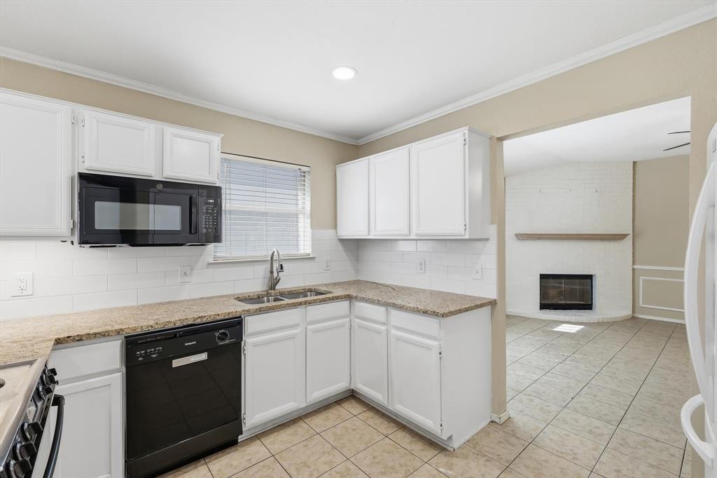 7733 Liz Lane Watauga, TX 76148 - Photo 10 of 27 Kitchen with black appliances, crown molding, a fireplace, white cabinets, and light stone countertops
