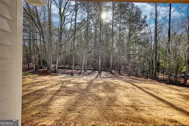 a view of an empty room with wooden floor fireplace and a window