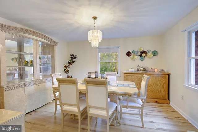 a dining room with wooden floor a chandelier a glass table and chairs