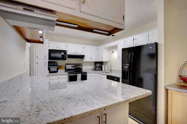a kitchen with stainless steel appliances granite countertop a table a refrigerator and a sink