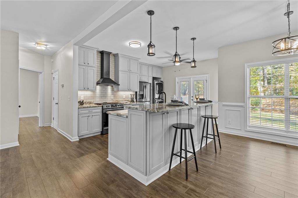 4230 Jonathan Lane Cumming, GA 30040 - Photo 13 of 57 a kitchen with stainless steel appliances kitchen island granite countertop a stove a sink a refrigerator and white cabinets with wooden floor