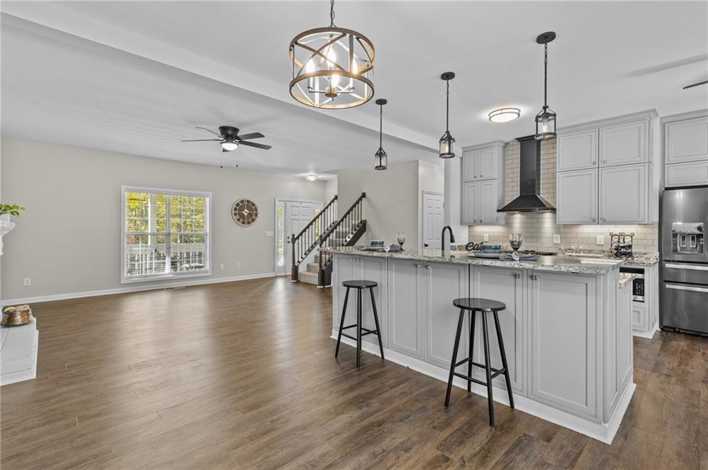 4230 Jonathan Lane Cumming, GA 30040 - Photo 20 of 57 a kitchen with kitchen island stainless steel appliances a table chairs in it and wooden floors