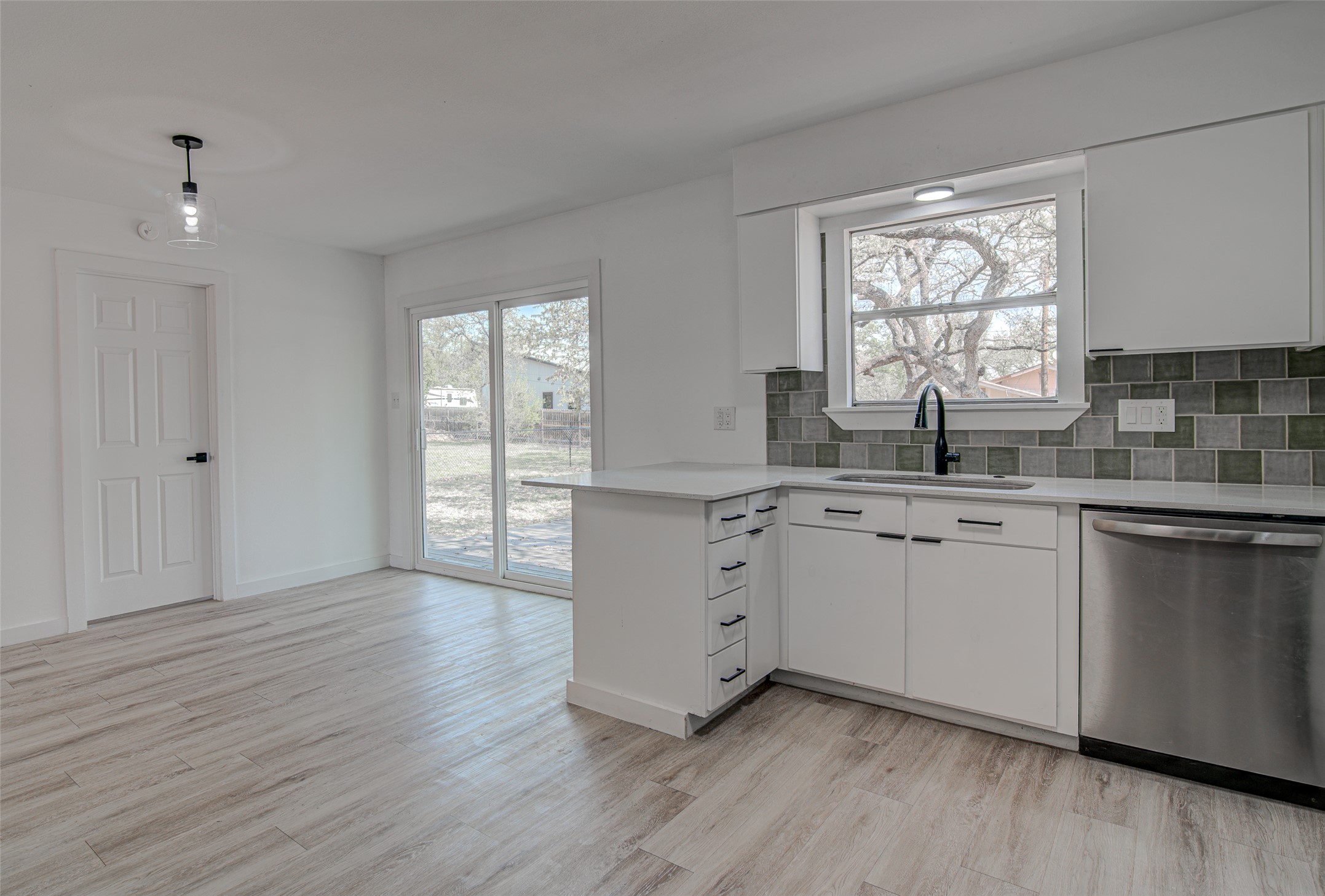 207 Haley Road Johnson City, TX 78636 - Photo 11 of 31 A well-lit kitchen with sleek white cabinetry, a generous window above the sink, and direct access to the outdoor space.