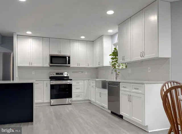 a kitchen with granite countertop white cabinets and stainless steel appliances