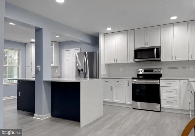 a kitchen with kitchen island granite countertop a sink a stove and cabinets