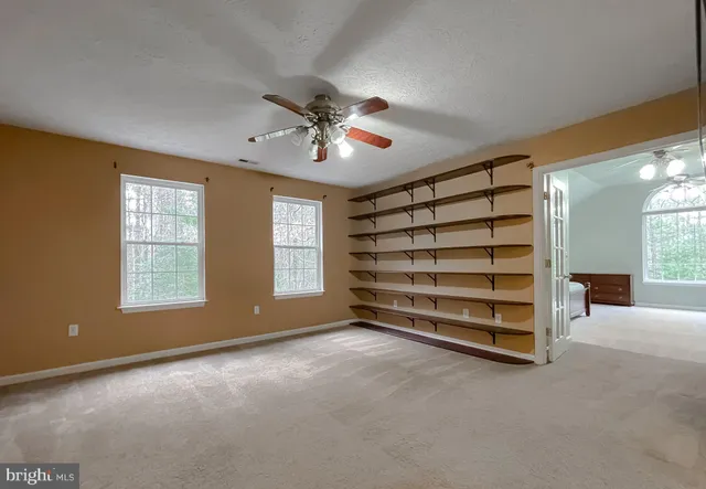an empty room with windows and fan